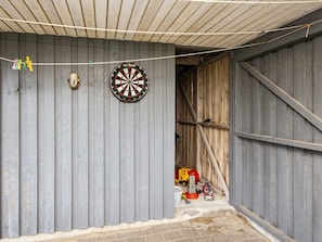 A room with a dartboard, a door, and a toy fire truck.