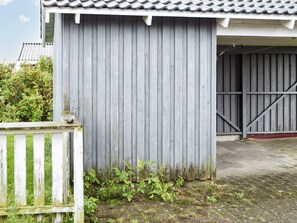 A corrugated metal building with a tiled roof, a wooden fence, and a concrete ground.