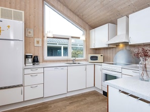A modern kitchen with white cabinets, a built-in oven, a microwave, and a coffee maker.
