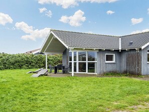 A single-story house with a grey tiled roof, a covered patio area, and a number '78' on the side.