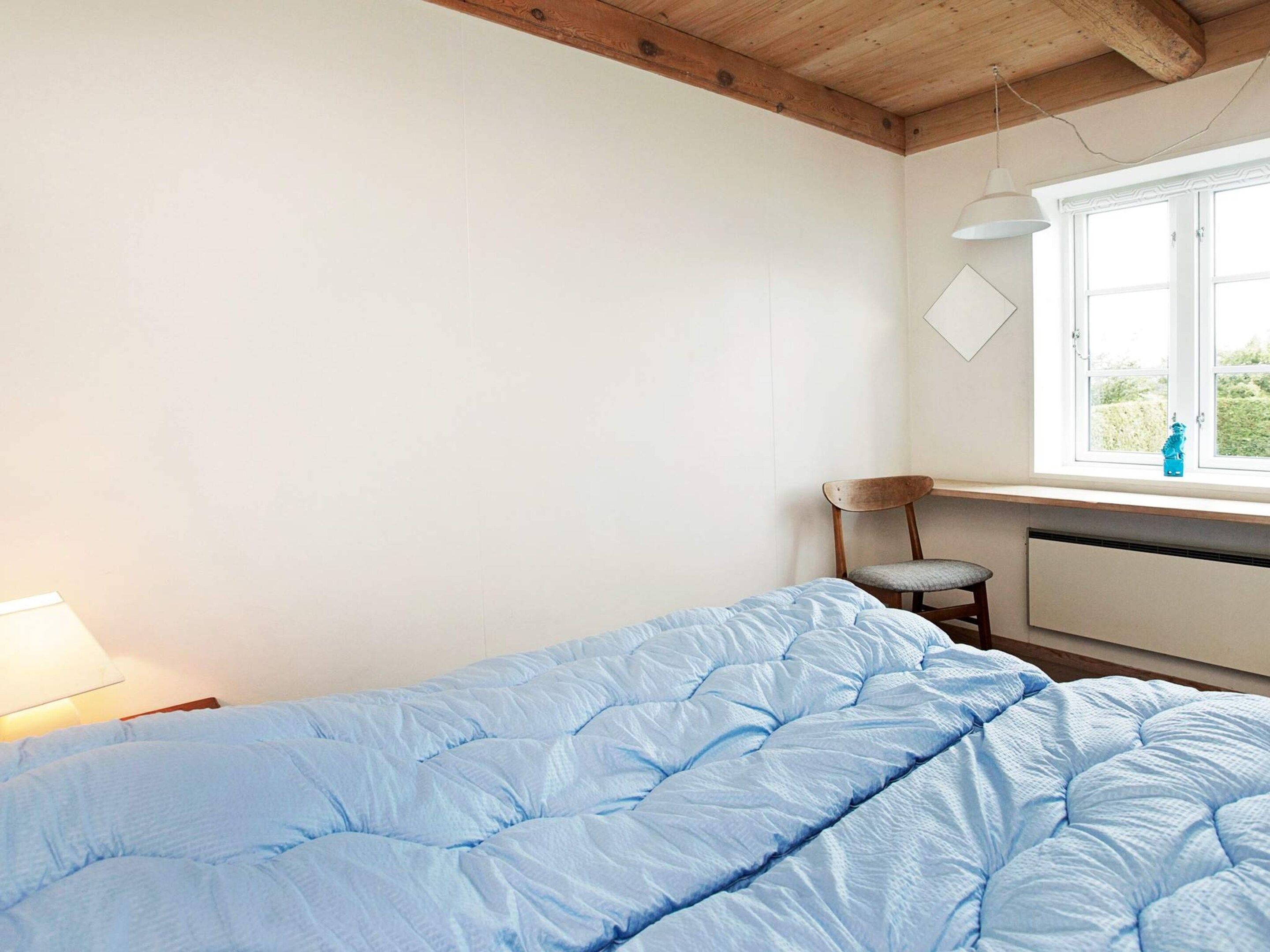 Et soveværelse med en enkeltseng, en stol, et skrivebord, et vindue og en radiator.
