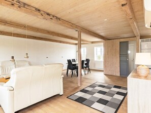 Un vaste espace de vie comprenant un canapé blanc, une table à manger avec des chaises et un tapis à carreaux.
