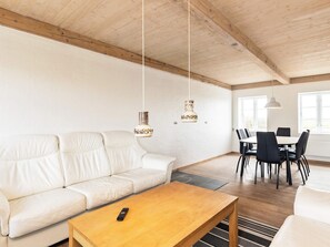 Un salon moderne avec un canapé en cuir blanc, une table basse en bois et un coin repas comprenant une table et des chaises.