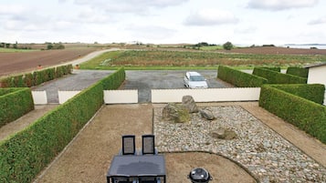 A patio with a table and chairs, a barbecue grill, and a car parked in the background.