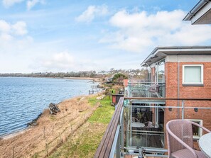 A waterfront property with a deck, outdoor seating, and a view of the water. - 4 Star Holiday Home in Hejls (Hejls)