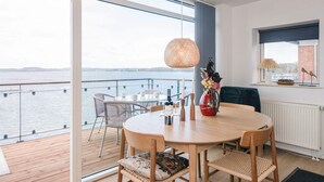Een eetgedeelte met een tafel, stoelen en uitzicht op het water.