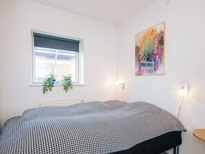 A bedroom with a bed, a window with blinds, two wall-mounted plants, a painting, and two wall sconces. - 4 Star Holiday Home in Hejls (Hejls)