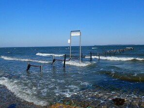 A coastal scene with a signpost in the water, waves, and a wooden pier. - 4 Star Holiday Home in Hejls (Hejls)