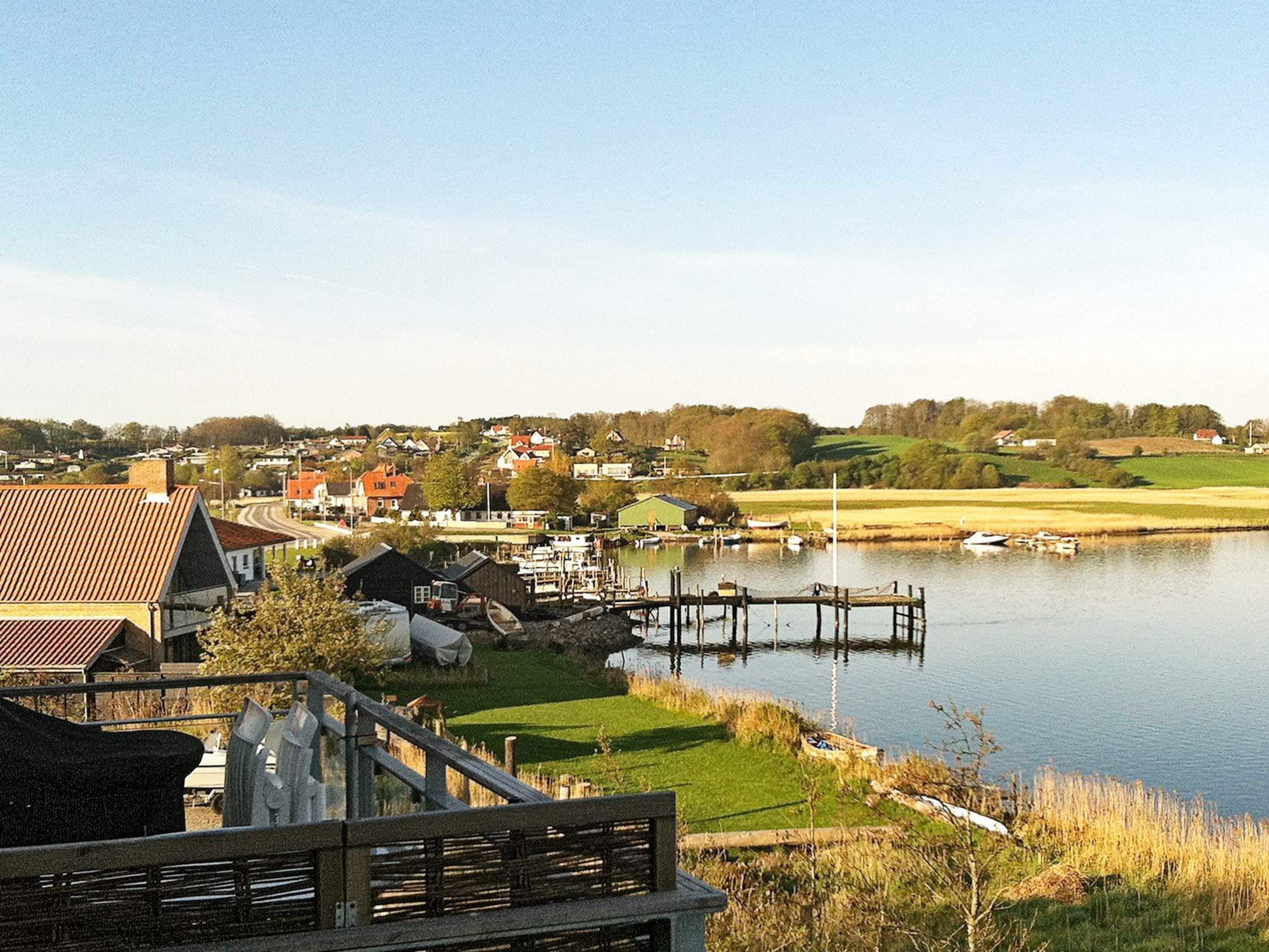 A lakeside village with houses, a dock, and boats.