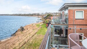 Een pand aan het water met een terras, buitentafels en uitzicht op het water.