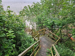 A wooden staircase leading through dense foliage towards a beach. - 4 Star Holiday Home in Hejls (Hejls)