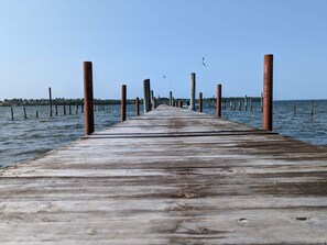 A wooden pier extending into calm water, with evenly spaced wooden posts and a clear sky. - 4 Star Holiday Home in Hejls (Hejls)