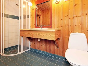 A bathroom with a wooden interior, a shower enclosure, a sink with a mirror, and a toilet. - Holiday Home in FÃ¥vang (Ringebu)