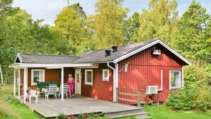 A red cabin with a porch, a covered outdoor seating area, and a small deck. - 4 Person Holiday Home in Hallabro (Hallaröd)
