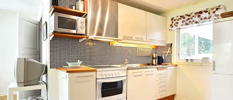 A modern kitchen with white cabinetry, a microwave, an oven, and a refrigerator.
