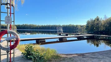 Un lago tranquilo con un muelle de madera que se adentra en el agua, rodeado de árboles.