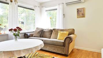 A cozy living room with a sofa, a round table, and a chandelier.