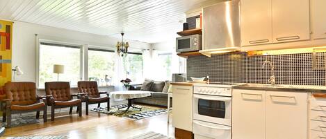 A modern kitchen with white cabinetry, a stainless steel range hood, and a built-in microwave.