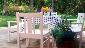 A wooden deck with two white chairs and a table covered with a checkered tablecloth. - 4 Person Holiday Home in Hallabro (Hallaröd)