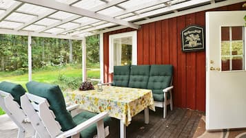 Un espacio al aire libre cubierto con mesa y sillas, una terraza de madera y una puerta con un letrero.