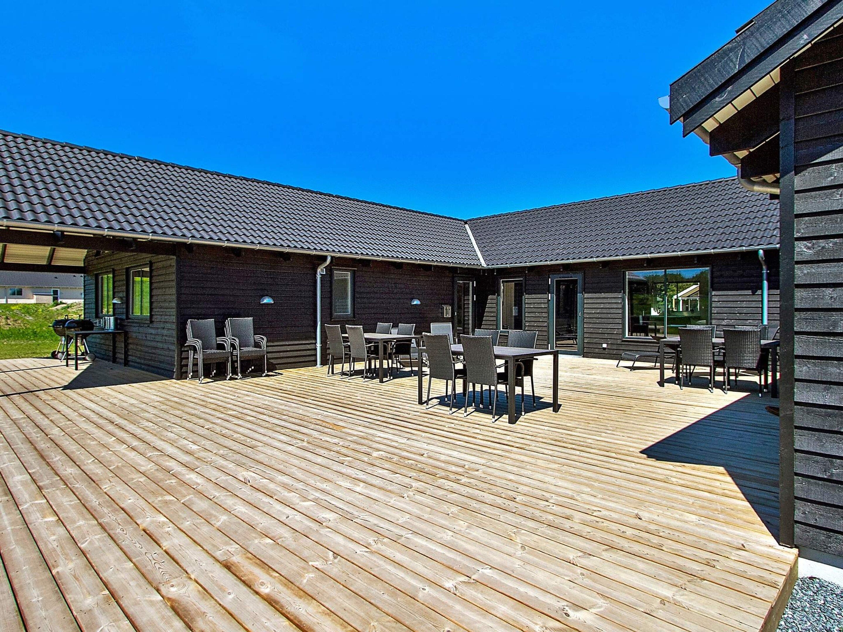 A covered outdoor patio with wooden decking and outdoor seating.