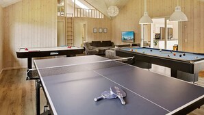 A room with a ping pong table, a pool table, and a billiards table. There is a sofa and a television in the background. - 5 Star Holiday Home in Vejby (Vejby)