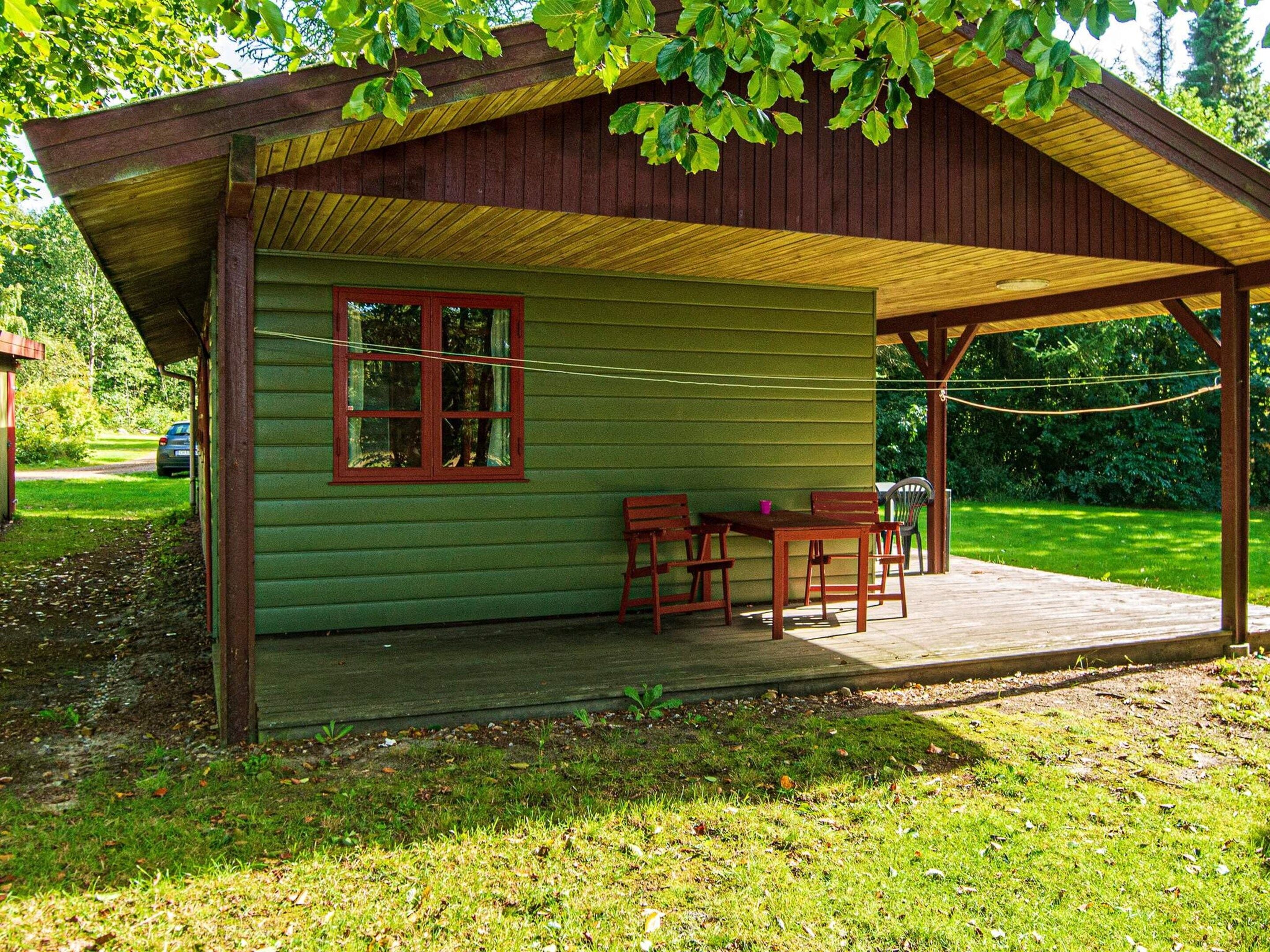 Een overdekt terras met een tafel, stoelen, een raam en een houten constructie.