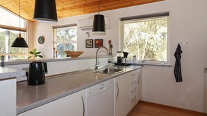 A modern kitchen with a large island, stainless steel appliances, and a window providing natural light. - Modern Holiday Home in Jutland With Sauna (Hadsund)