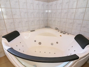 A large, white, freestanding bathtub with black seats and a glass door, set against a tiled wall. - Modern Holiday Home in Jutland With Sauna (Hadsund)