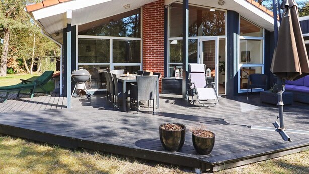 A modern house with a covered patio, outdoor seating, and a barbecue grill. - Modern Holiday Home in Jutland With Sauna (Hadsund)