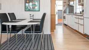 Una cucina moderna con mobili bianchi ed elettrodomestici in acciaio inossidabile. C'è un'area pranzo con un tavolo rotondo e sedie nere. Un quadro incorniciato è appeso al muro sopra il tavolo.