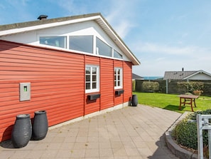 A red wooden house with white trim, a tiled patio, and a view of the sea. - Seaside Escape With Views - By Traum Ferienwohnungen (Hejls)