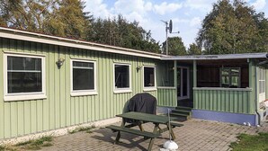 A green building with a covered outdoor seating area and a satellite dish. - 8 Person Holiday Home in Stege (Stege)