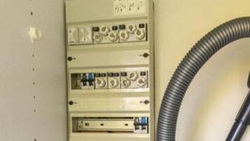 A utility panel with multiple switches and indicators, a cable, and a label with text.
