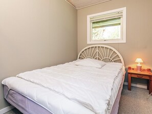 Une chambre à coucher avec un lit, une table de chevet, une lampe et une fenêtre avec des stores.