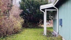 A building with a green exterior, a white porch, and a grassy yard. - 8 Person Holiday Home in Stege (Stege)