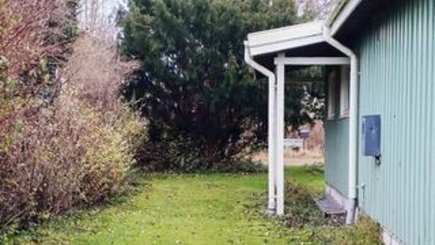 A building with a green exterior, a white porch, and a grassy yard. - 8 Person Holiday Home in Stege (Stege)