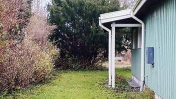 A building with a green exterior, a white porch, and a grassy yard.