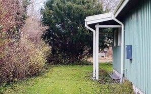 Un bâtiment à l’extérieur verdoyant, avec un porche blanc et une cour couverte d’herbe.