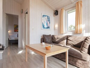 A cozy room with a wooden floor, a brown sofa, a small table with a candle, and a painting on the wall. - Holiday Home in GrÃ¶mmitz (Groemitz)
