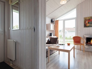 A room with a wooden floor, a table, a sofa, a fireplace, and a view of the outdoors. - Holiday Home in GrÃ¶mmitz (Groemitz)