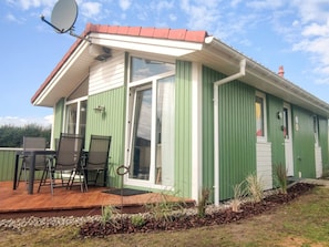 A green building with a covered patio, a satellite dish, and a door with a number. - Holiday Home in GrÃ¶mmitz (Groemitz)