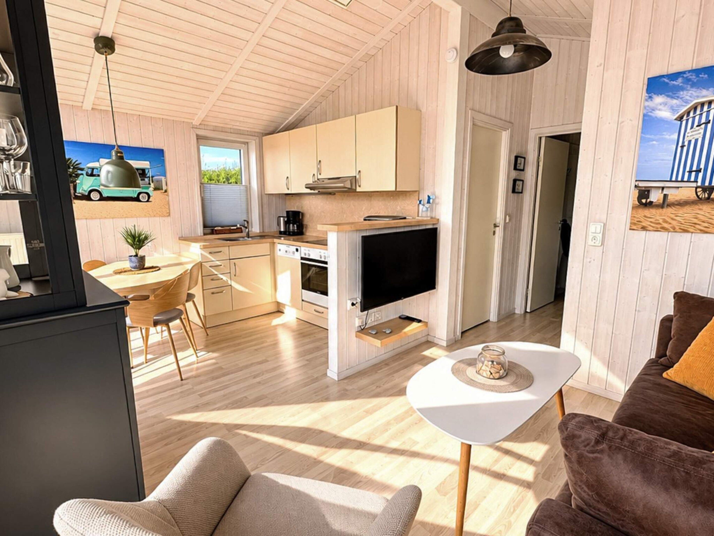Une cuisine moderne avec des meubles en bois, un coin repas avec une table et des chaises, et un salon avec un canapé et une table basse.