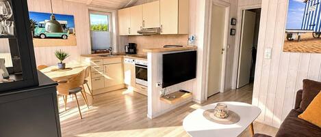 Une cuisine moderne avec des meubles en bois, un coin repas avec une table et des chaises, et un salon avec un canapé et une table basse.