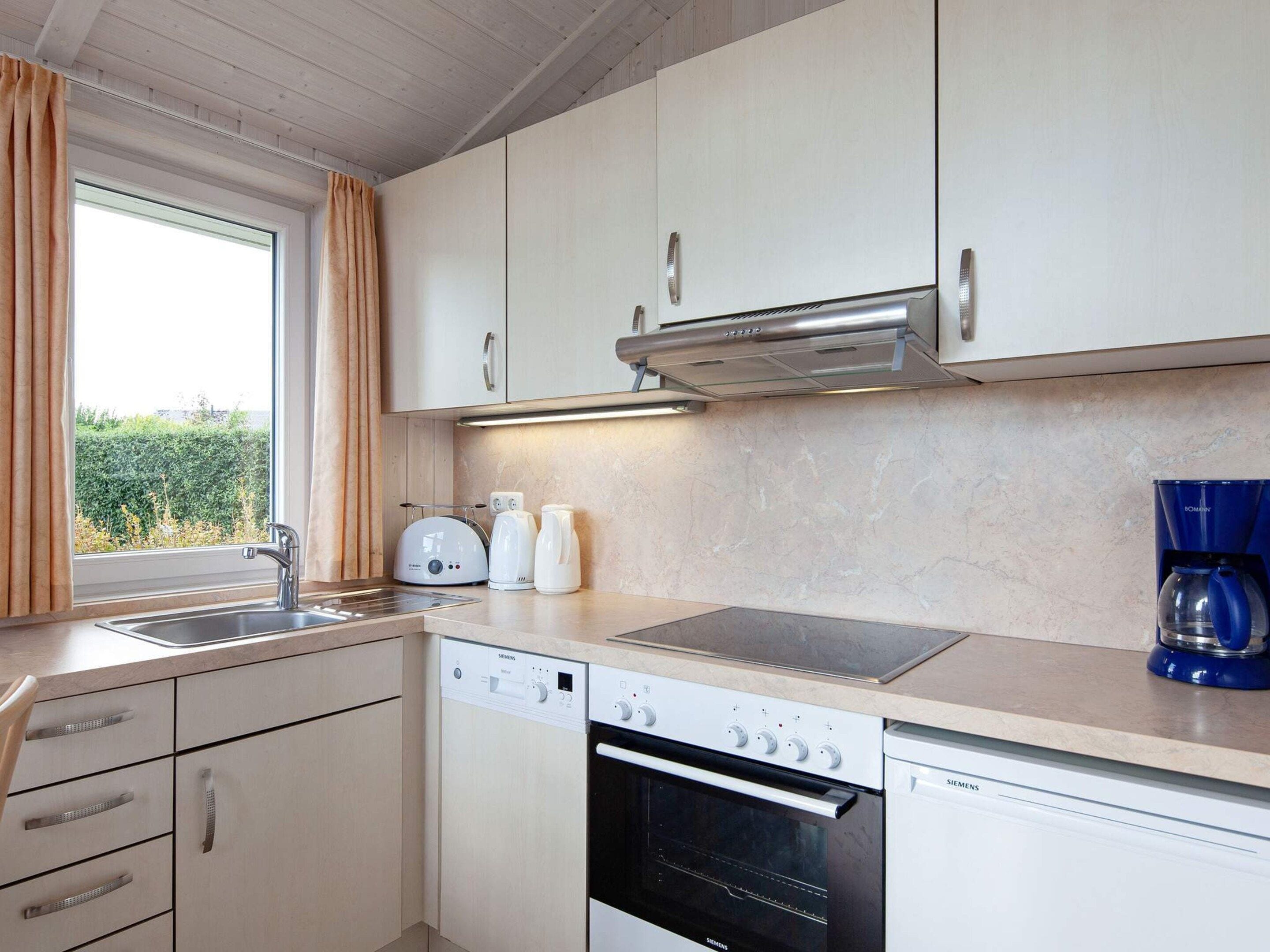 A modern kitchen with a dishwasher, oven, and a coffee maker.