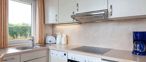 A modern kitchen with a dishwasher, oven, and a coffee maker.