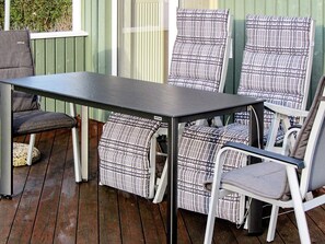 A patio with a table and chairs, a cushion, and a small round table. - Holiday Home in GrÃ¶mmitz (Groemitz)