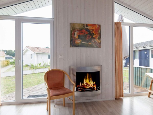 Una habitación con chimenea, una silla y vistas al exterior.