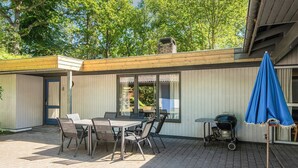 A patio with a table and chairs, a barbecue grill, and a blue umbrella. - Tranquil Holiday Home in Glesborg with Hot Tub & Sauna (Glesborg)