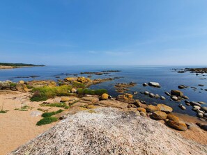 A rocky shoreline with clear water and distant land. - 4 Person Holiday Home in Svaneke (Svaneke)